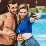 Mooie jonge koppel met flessen bier selfie nemen op smartphone