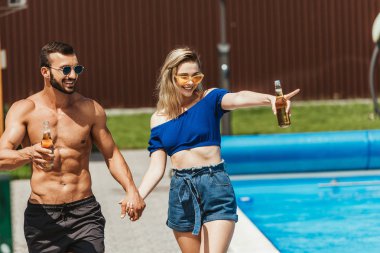 Elele, havuz kenarında işaret kız bira şişeleri ile mutlu çift