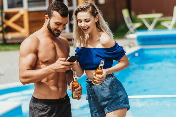 Stel Met Behulp Van Smartphone Bedrijf Flessen Bier Bij Zwembad — Stockfoto