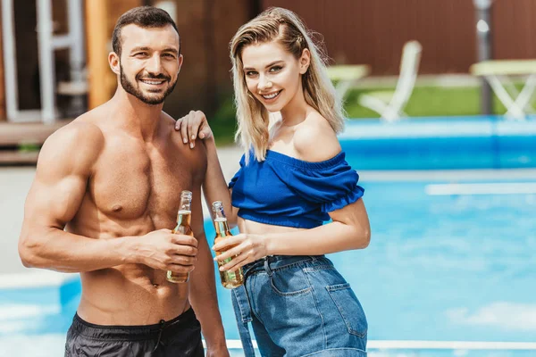 幸福美丽的夫妇在池畔的啤酒瓶 — 免费的图库照片