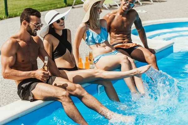 多文化的朋友与瓶啤酒放松在游泳池 — 图库照片