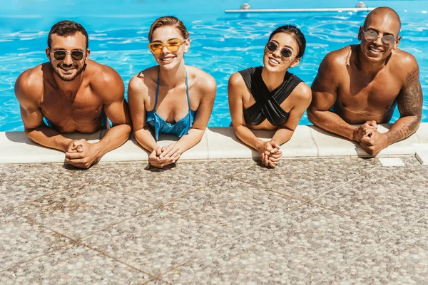 Amigos Multiculturales Trajes Baño Gafas Sol Posando Piscina —  Fotos de Stock