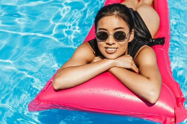 水着やスイミング プールで膨脹可能なマットレスで日光浴サングラスでアジアの少女  — 無料ストックフォト