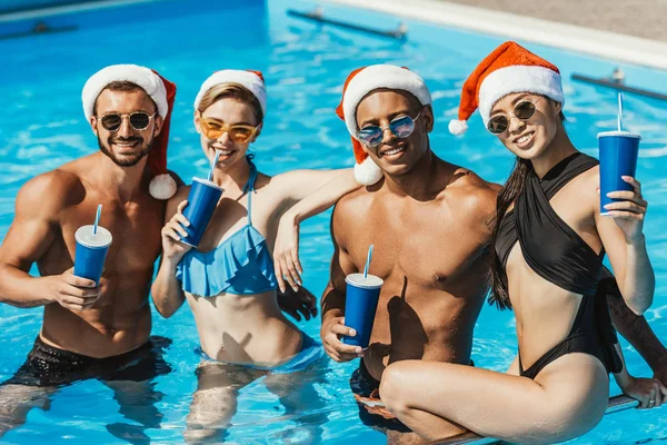 Amigos Multiétnicos Sombreros Santa Con Bebidas Piscina — Foto de Stock