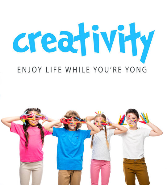 schoolchildren having fun and showing painted hands with smiley icons isolated on white, with "creativity - enjoy life while youre yong" lettering