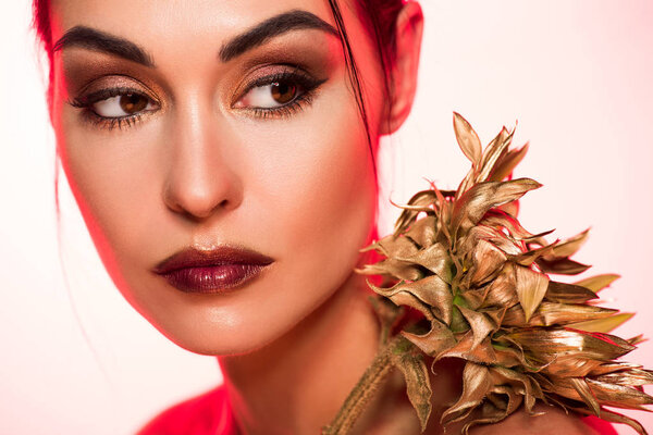 Portrait of elegant girl with golden sunflower posing for fashion shoot, red toned picture