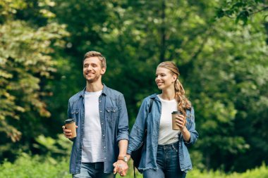 kahve yeşil park ile birlikte yürüyen genç çift kağıt bardak ile gülümseyen
