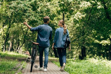 Bisiklet park ile yürüyüş ile kot gömlek güzel genç çiftin arka görünüm