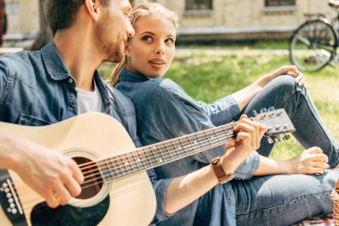 yakışıklı genç adam parkta dinlenirken kız arkadaşı için gitar çalmak