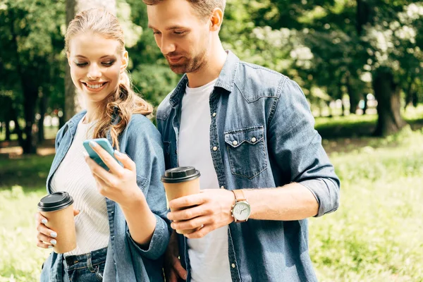 Счастливая Молодая Пара Бумажными Стаканчиками Используя Смартфон Вместе Парке — стоковое фото