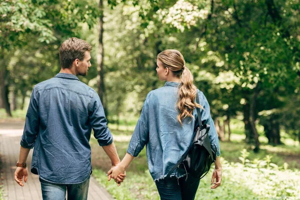 美丽的年轻夫妇的后视图牛仔衬衫步行公园 — 图库照片