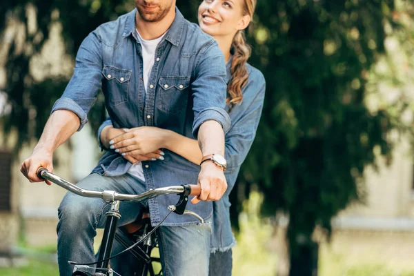 公園で一緒に自転車に乗って若いカップルのショットをトリミング  — 無料ストックフォト
