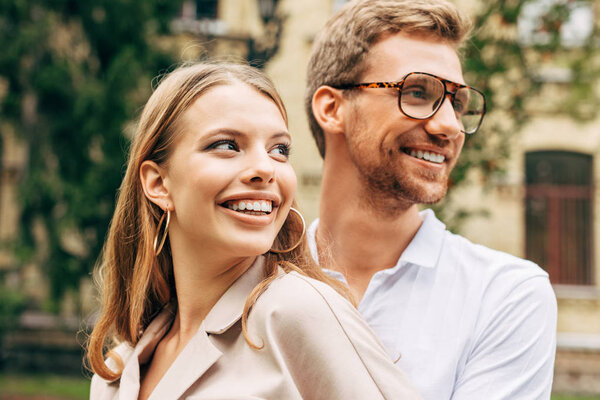 close-up portrait of smiling young couple in stylish clothes looking away