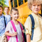 Group of adorable classmates near school bus