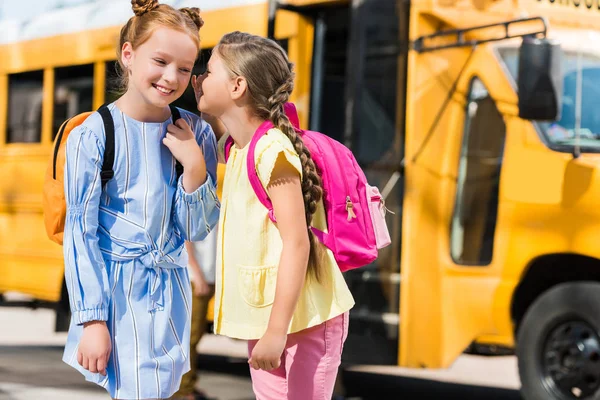 幸せな小さな女子学生の学校のバスの前でおしゃべり — ストック写真