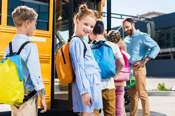 Vackra Skolflicka Tittar Kameran Stående Nära Skolbuss Med Klasskamrater Och — Stockfoto