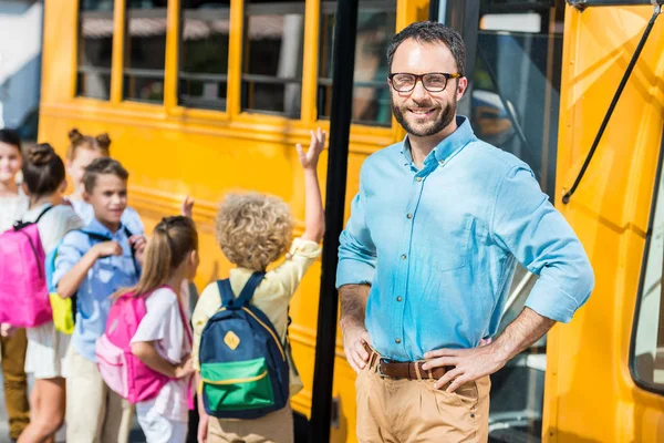 Knappe Bebaarde Leraar Camera Terwijl Leerlingen Invoeren Van Bus Van — Stockfoto