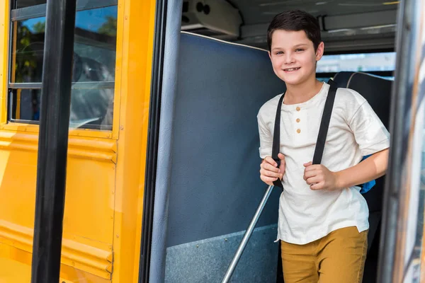 Lachende Schooljongen Met Rugzak Permanent Schoolbus Camera Kijken — Gratis stockfoto