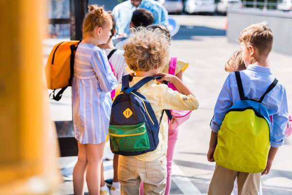 rear view of group of scholars near school bus