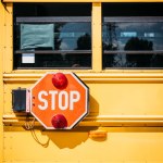 Zijaanzicht van de bus van de school met stopbord