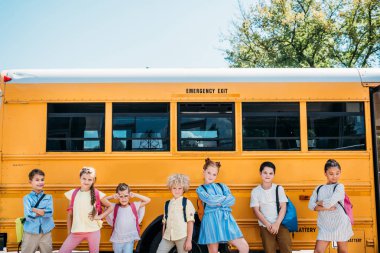 group of happy scholars posing in front of school bus clipart