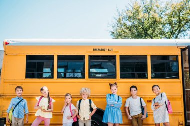 group of adorable pupils posing in front of school bus clipart