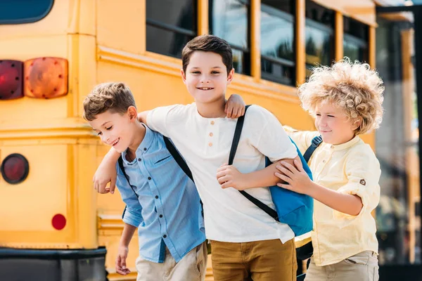 学校のバスの前で一緒に楽しんで愛らしい小さな男子生徒 — ストック写真