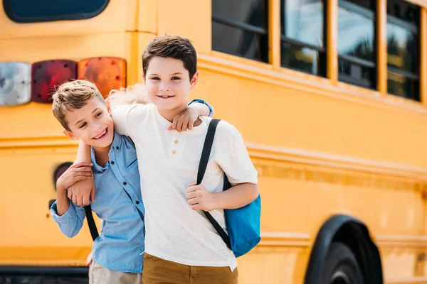 Smiling Little Schoolboys Embracing Front School Bus — Stock Photo, Image