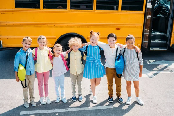 Grupp Bedårande Skolbarn Står Framför Skolbuss Och Tittar Kameran — Stockfoto
