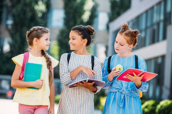 group of beautiful schoolgirls with notebooks spending time together after school