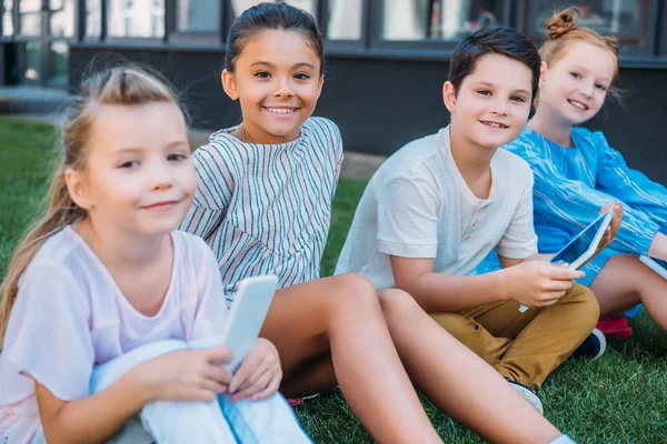 Gruppe Entzückender Schulkinder Mit Dugutal Geräten Die Auf Gras Sitzen — Stockfoto