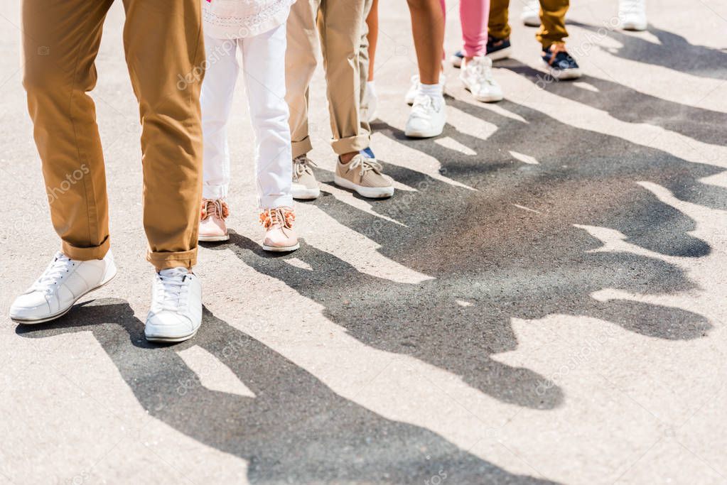 cropped shot of one adult and children in various shoes and pants standing in row