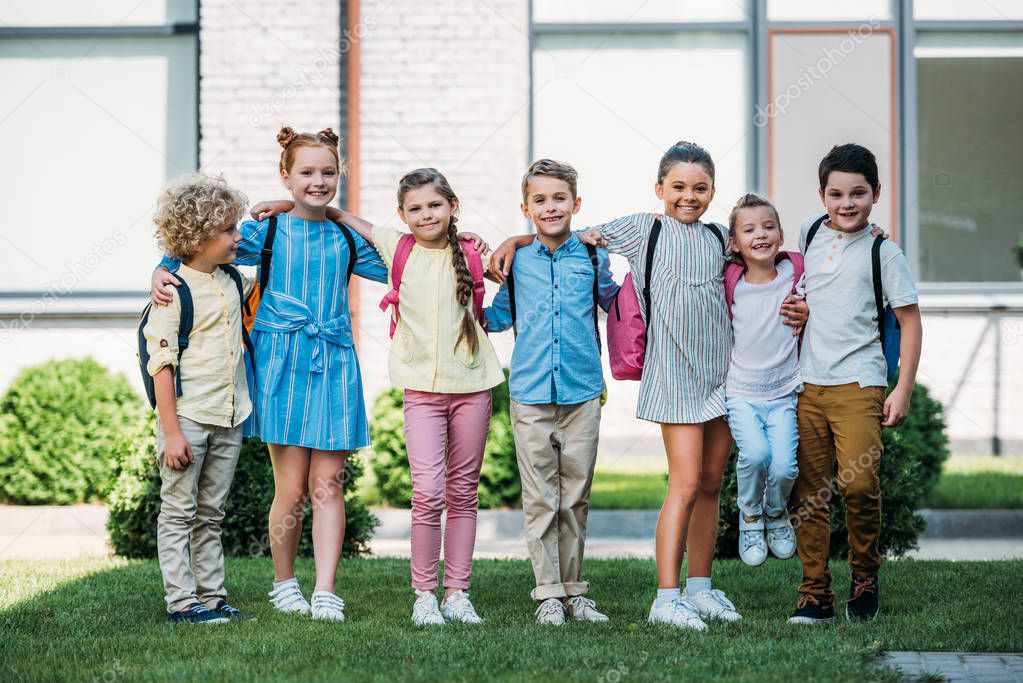 group of adorable schoolchildren standing at school garden and looking at camera