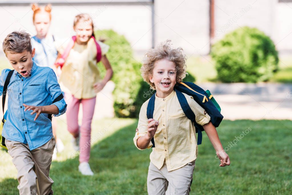 happy schoolboy with classmates runing by school garden