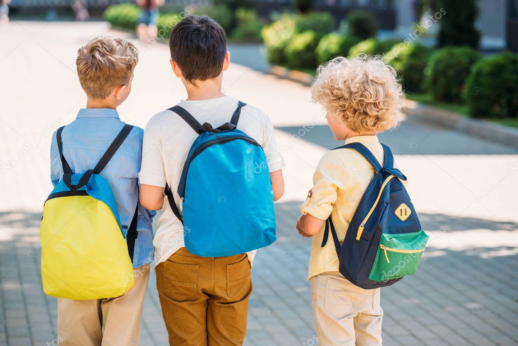 rear view of pupils with backpacks walking together