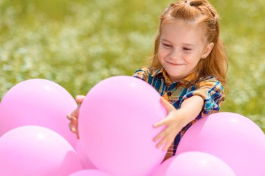 yaz alanında pembe balonlu gülümseyen sevimli çocuk portresi