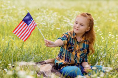 Amerikan bayrak direğine alanında yeşil çimenlerin üzerinde dinlenme ile şirin çocuk