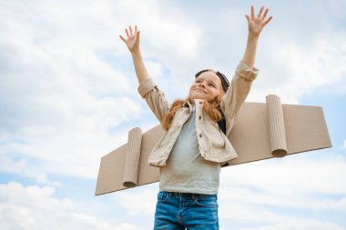 kağıt uçak kanatları olan çocuk ve mavi bulutlu gökyüzü karşı uzanmış kollarıyla koruyucu gözlük düşük açılı görünümü