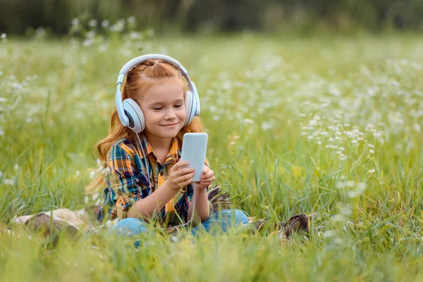 Mosolygó Gyermek Fejhallgató Használ Smartphone Miközben Pihen Takaró Rét Vadvirágok — Stock Fotó