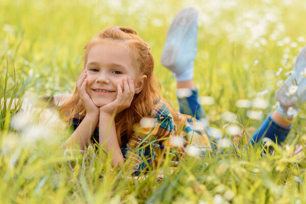 портрет маленького улыбающегося ребенка, покоящегося на зеленой траве на лугу
