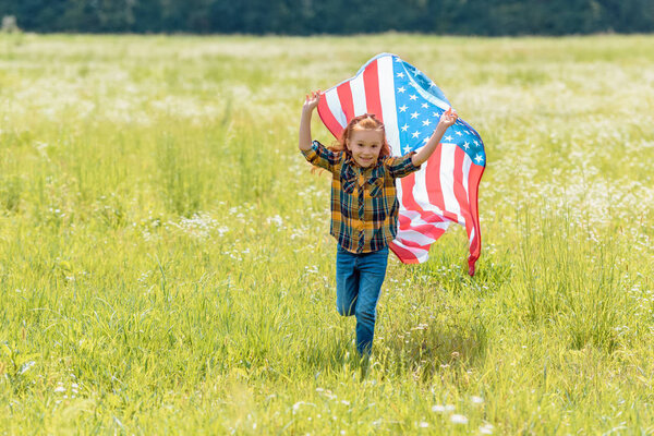 cheerful child running in field with american flag in hands