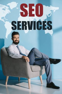 formal giyim Dünya Haritası ve Seo Hizmetleri ile mavi gri koltukta oturan başarılı geliştirici