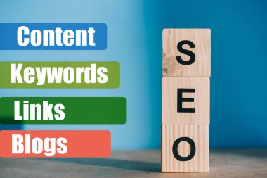 SEO word made from wooden blocks on blue background with Content, Keywords, Links, Blogs signs clipart