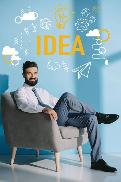 Hombre Negocios Sonriente Sentado Sillón Gris Azul Con Iconos Ideas — Foto de Stock