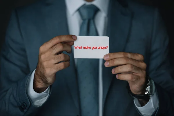 ビジネス カード ユニークなものですか の文字を保持しているスーツのビジネスマンのトリミング ビュー — ストック写真