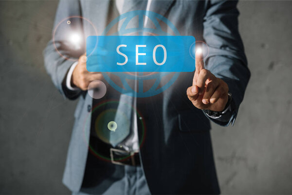 cropped view of developer in formal wear pointing at SEO sign