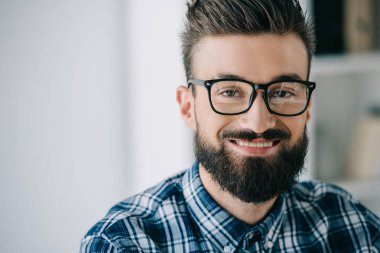 yakın çekim gözlük kameraya bakarak sakallı gülümseyen adam portresi