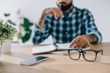 İşyerinde oturan defter ile ekose gömlek adama kadeh kırpılmış