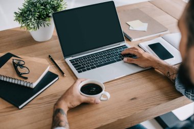 kırpılmış bir kahve laptop ve holding çalışma alanı kullanan adam görünümünü