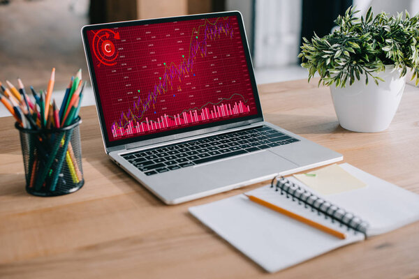 laptop with red business graph standing at workspace